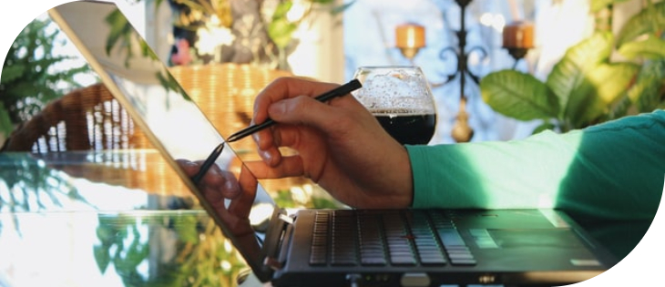 A person holding a pen and drinking from a glass. 